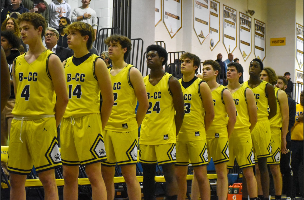 The Boys Basketball team stands tall during the pregame anthem.