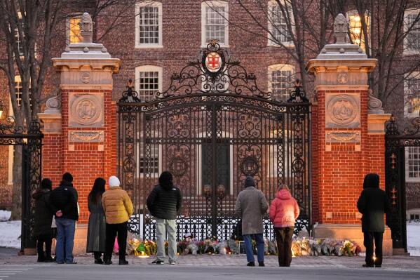 Visitors pause at a makeshift memorial for the victims of Saturday’s shooting, at the Van Wickle Gate at Brown University, Monday, Dec. 15, 2025, in Providence